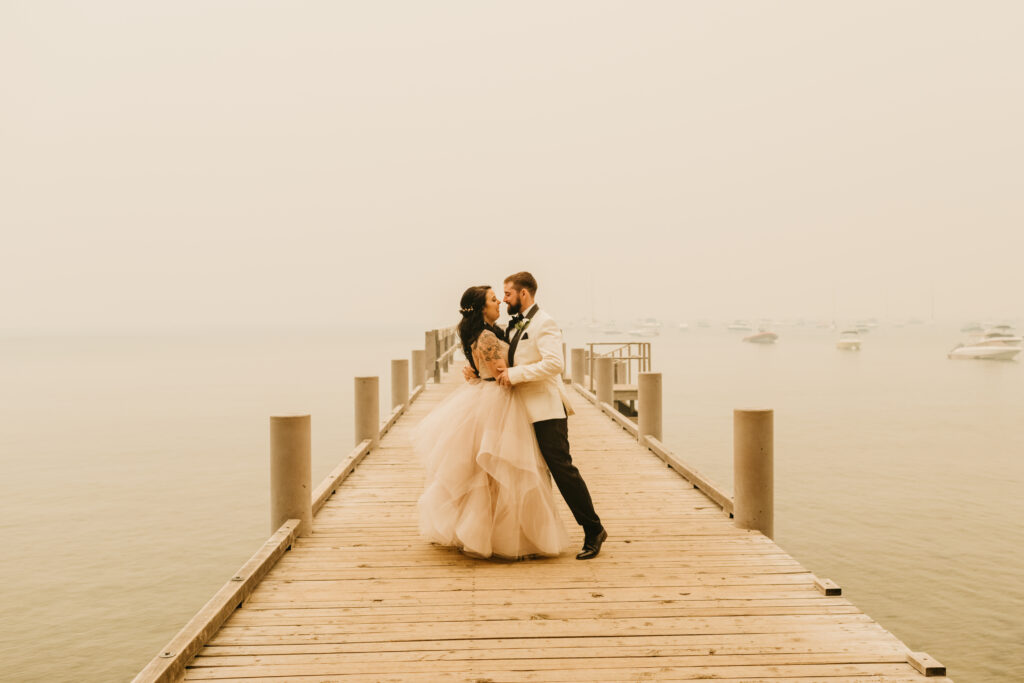 Bride and Groom on Lake Tahoe Dock while wearing wedding attire | Valhalla Tahoe Summer Wedding