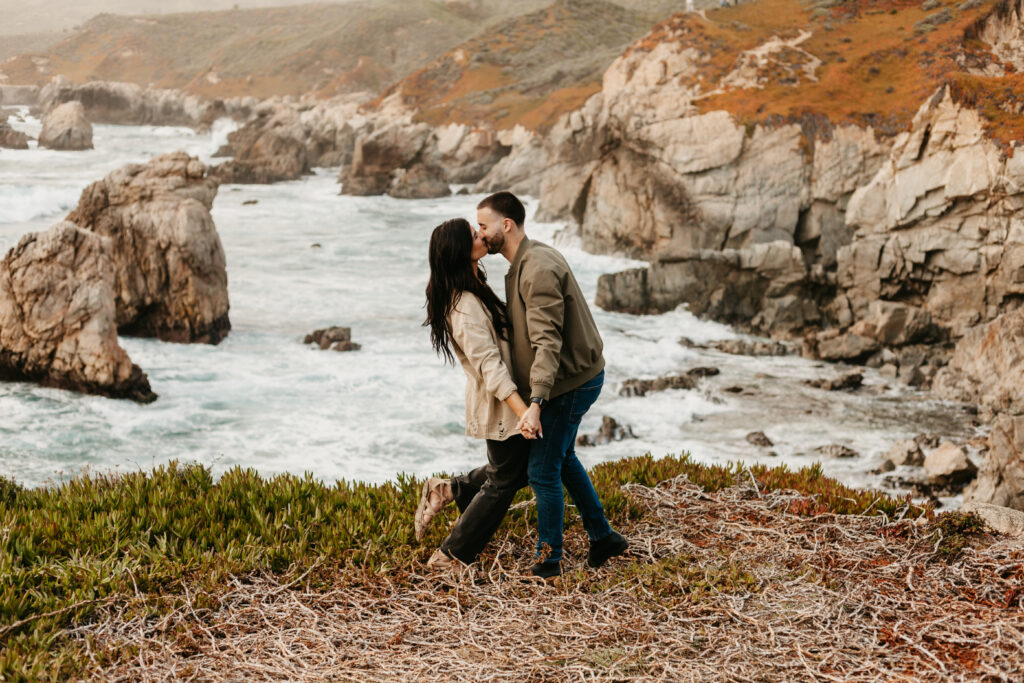 A couple kisses one another during their coastal couples session in Big Sur, California.